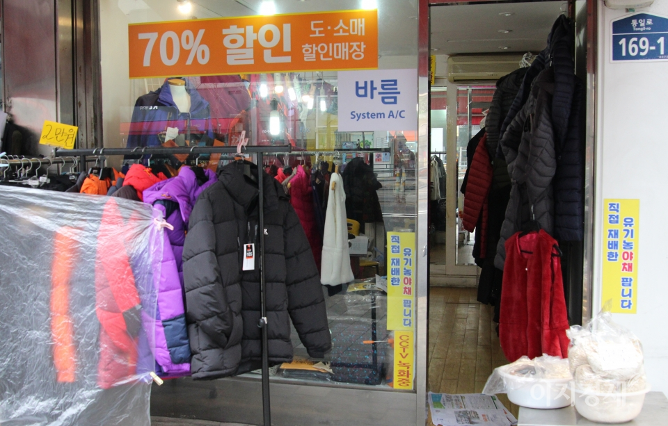시장 옆에 자리한 한 옷가게는 옷을 대폭 할인해 판매하고 있지만 매출이 오르지 않자, 궁여지책으로 유기농 야채와 엿기름(오른쪽 하얀 비닐봉투)을 팔고 있다. 사진=문룡식 기자