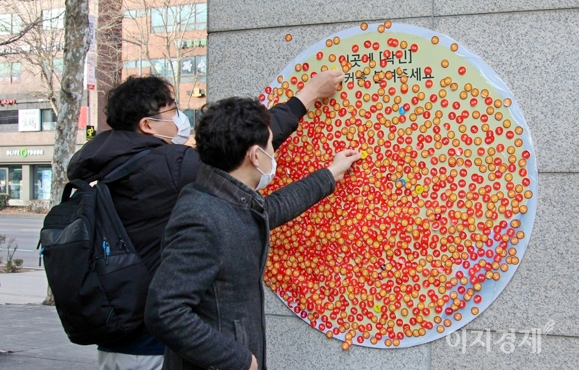 병원에서 일을 마친 두명의 30대 남성이 병원 출구에 마련된 ‘확인’ 딱지 부착판에 자신의 ‘확인’ 딱지를 붙이고 있다. 사진=김보람 기자