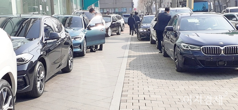 카캐리어에서 하차한 BMW 차량이 인도와 전시장 소유 주차공간을 차지했다. 지하철7호선 내방역 방향으로 가는 주민들이 어깨를 피하면서 불편하게 걷고 있다. 사진=이민섭 기자