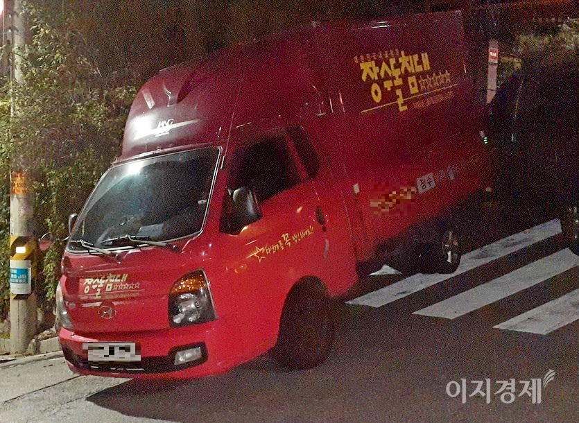 수도권 한 도시 주택가 이면도로 횡단보도에 장수돌침대 배송 차량이 주차돼 있다. 이 차량은 항상 밤에 이곳에 주차한다. 아울러 이 차량은 경사로 주차방법도 위반하고 있다. 경사로 주차시 상황에 따라 앞바퀴를 오른쪽이나 왼쪽으로 완전히 돌려야 한다. 횡단보도 주차와 경사로 주차 방법 위반, 모두 과태료 부과 대상이다. 장수돌침대 배송 차량이 주차된 곳 바로 옆과 200여미터 떨어진 곳에는 공영주차장이 각각 자리하고 있다. 사진=이민섭 기자