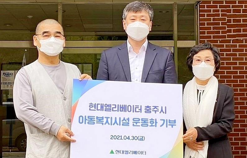 현대엘리베이터 이천호 사회공헌팀장(가운데)이 아동복지시설인 충주 진여원 원장 혜원스님(왼쪽)과 김낙정 충주자원봉사센터장(오른쪽)에게 운동화를 전달하고 기념 사진을 찍고 있다. 사진=현대엘리베이터