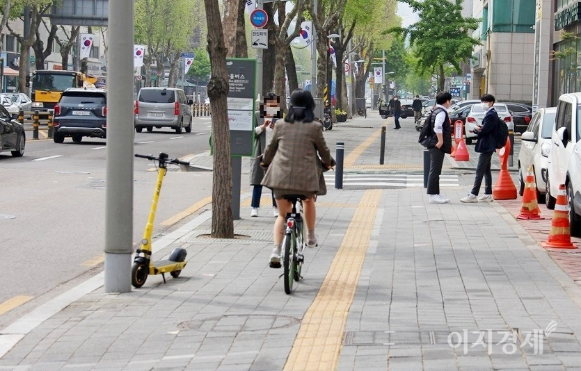 자전거는 도로교통법 규제를 받는 엄연한 자동차다. 이륜차 주행방법 따라 차도 우측으로 주행해야 한다. 한 중년 여성이 자전거를 타고 인도를 달리고 있다. 경찰청이 부착한 이륜차 안전운전 포스터가 무색하다. 사진=정수남 기자