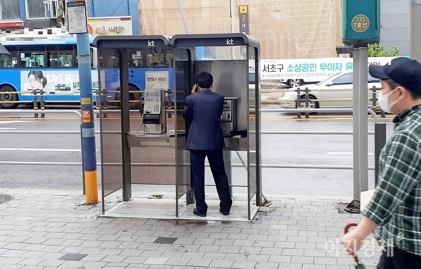 서울 지하철 7호선 내방역 인근 공중전화 부스. 이날 비가 부슬부슬 내렸다. 한 중년 신사가 공중전화를 이용하고 있다. 사진=정수남 기자