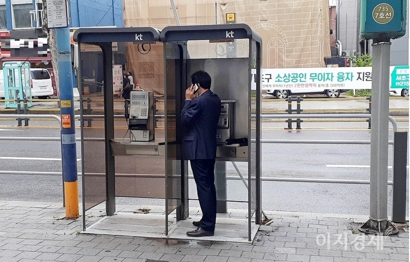 신사가 옆으로 돌아서자 비를 피해 공중전화부스에서 휴대폰으로 통화하고 있는 모습으로 변했다. 사진=정수남 기자