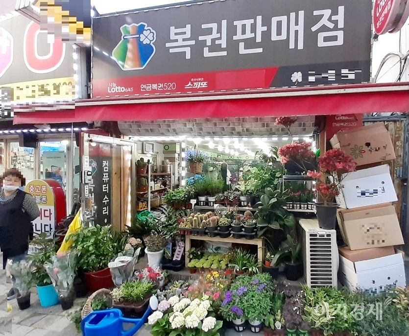 로또판매점과 이동통신대리점을 사이에 두고 있는 꽃집이 페업한 로또 가게를 차지하면서 가게를 넓힌 것이다. 왼쪽 꽃집 주인 아주머니가 “꽃 로또”라며 웃고 있다. 사진=정수남 기자