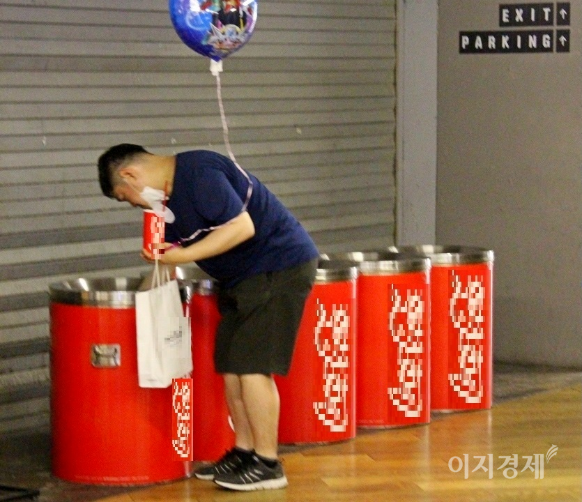 한 30대 남성이 쓰레기통을 뒤져 관람객이 버린 팝콘과 음료수 등을 찾아 먹고 있다. 사진=정수남.