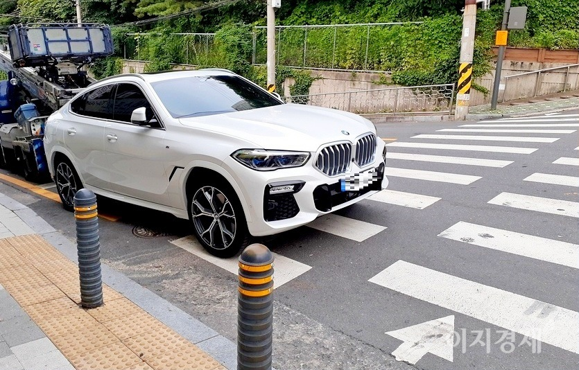 BMW X6 xDrive40i(가솔린)가 횡단보도에 걸쳐 주차해 있다. 차를 빼달라고 하자, 차주가 바로 옆 가게에서 나온다. 사진=정수남 기자