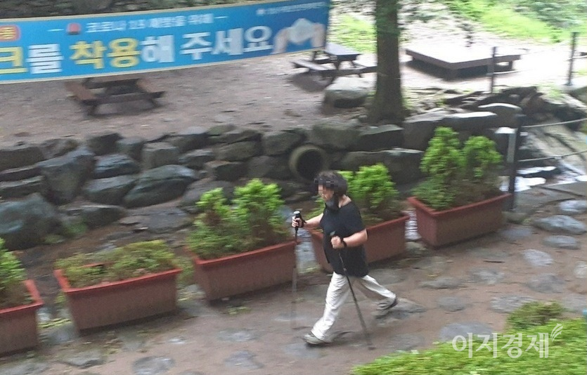 공원 내 다른 장소에서도 한 노인이 마스크를 턱에 걸치고 걷고 있다. 마스크 착용을 알리는 현수막이 무색하다. 사진=선호균 기자