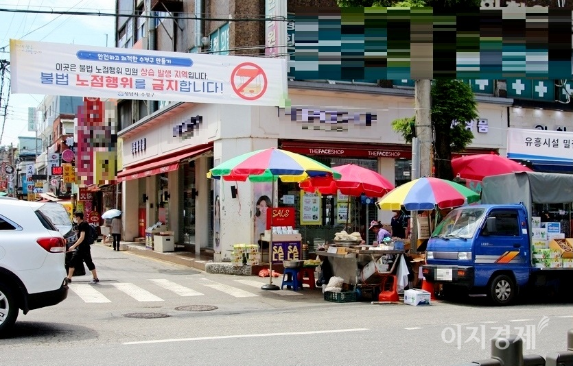 다만, 전시행정도 여전하다. 지난 주말 성남시 수정구 중앙시장 인근 도로다. 수정구가 불법노점 행위를 금지한다고 현수막을 걸었지만, 딱 거기까지다. 이곳은 유동인구가 많아 노점이 항상 인도의 반을 차지하고 있다. 사진 오른쪽에 있는 손수레와 포터트럭 노점은 1년 365일 이 자리를 차지하고 있다. 횡단보도 초입이라 안전사고와 함께 도로 횡단이 크게 불편하다. 사진=정수남 기자