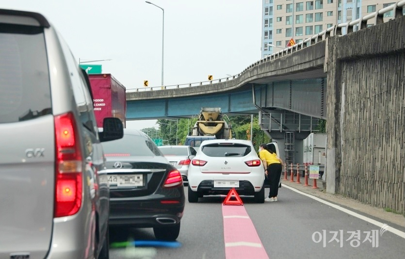 클리오의 여성운전자가 내려 차량 후면에 비상 삼각대를 설치했으나, 차랭과의 간격이 2m 정도로 너무 짧다. 아울러 삼각대 설치 후 수신호나 경광등으로 후속 차량의 서행과 함께 우회를 유도해야 하지만, 휴대폰으로 보험사 비상출동 신고에만 열심이다. 사진=정수남 기자