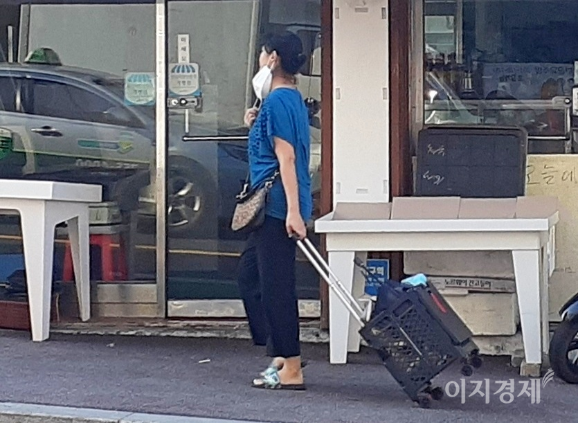 7일 아침 한 60대 여성이 마스크를 귀에 걸치고 인도를 걷고 있다. 사진=이지경제