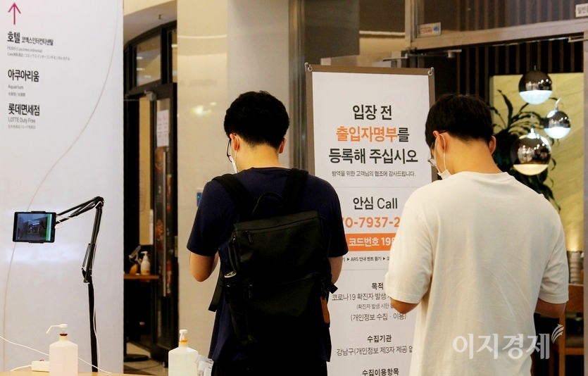 15일 코로나19 신규 확진자가 1556명 발생해 일요일 기준으로 사상 최대를 기록했다. 현재 사회적 거리두기 4단계가 발효된 수도권의 경우 다중시설 입장을 위해서는 암심콜이나 큐알코드 체크인을 해야 한다. 서울 삼성동 코엑스에 들어가기 위해 두 남성이 큐알코드 체크인 등을 하고 있다. 사진=이지경제