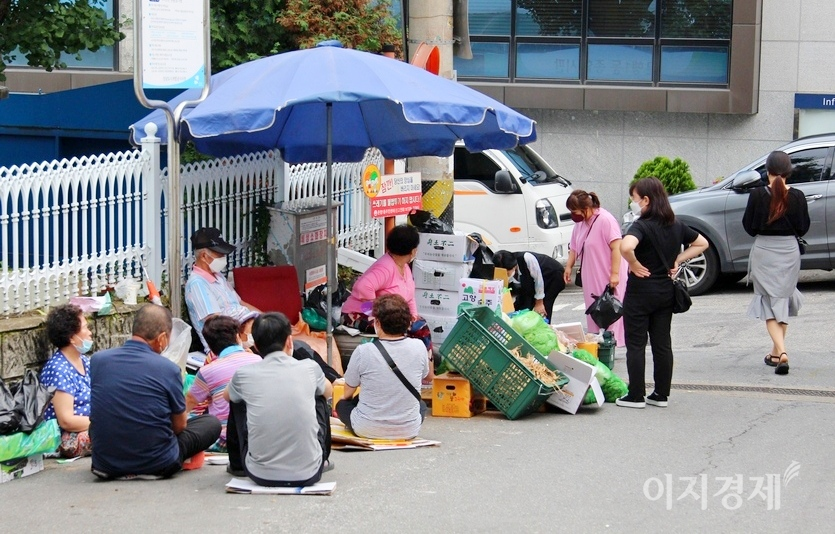 70대 이상 노인들이 골목에 야채 난전을 펼친 주면에 옹기종기 모여 노(N0)변담화를 하고 있다. 이중 일부는 마스크를 코에 걸쳤고, 일부는 마스크를 하지 않았다. 사진=정수남기자