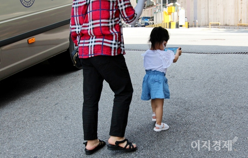 서너살 아이가 칭얼대며 집에 가지않으려 하자, 할머니로 보이는 70대 노인이 아이에게 스마트폰으로 무엇인가를 보여준다. 사진=정수남 기자