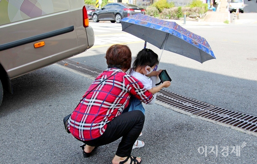 이번에는 아이가 스마트폰 삼매경에 빠져 걸음을 늦추자 할머니가 아이를 껴안아 들고 있다. 사진=정수남 기자.