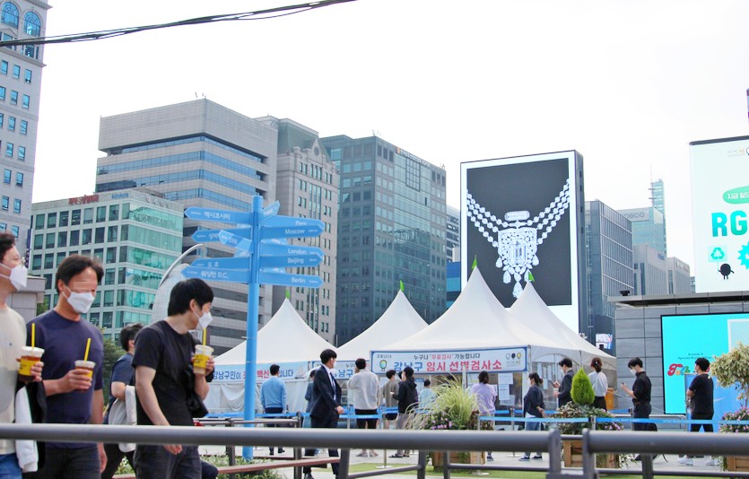 국내 코로나19 확산세가 이어지면서 13일 신규 확진자 수는 1900명대 중반으로 2000명대에 근접했다. <br>서울 삼성역에 설치된 강남구 코로나19 임시선별검사소 앞에 100여m 가랑 늘어선 검사 대기줄을 지나가는 시민들이 힐끗지켜보고 있다. 사진=김성미 기자