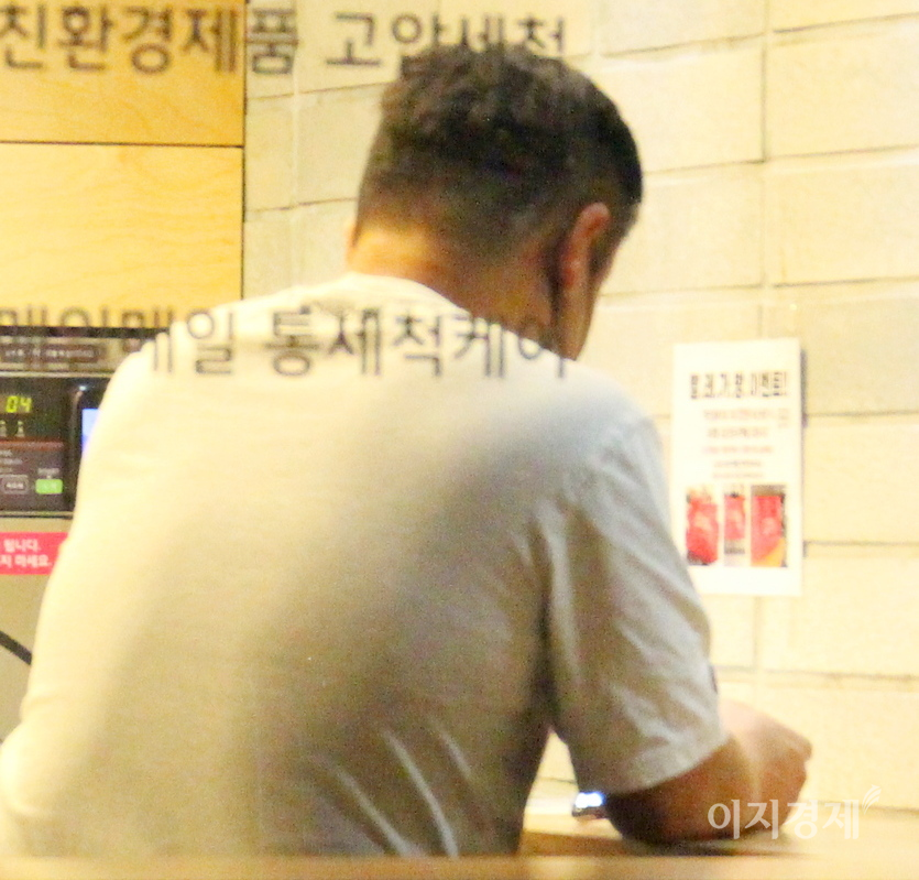 한 중년 남성이 새벽에 스마트폰 삼매경에 빠졌다. 셀프 빨래방이다. 사진=정수남 기자