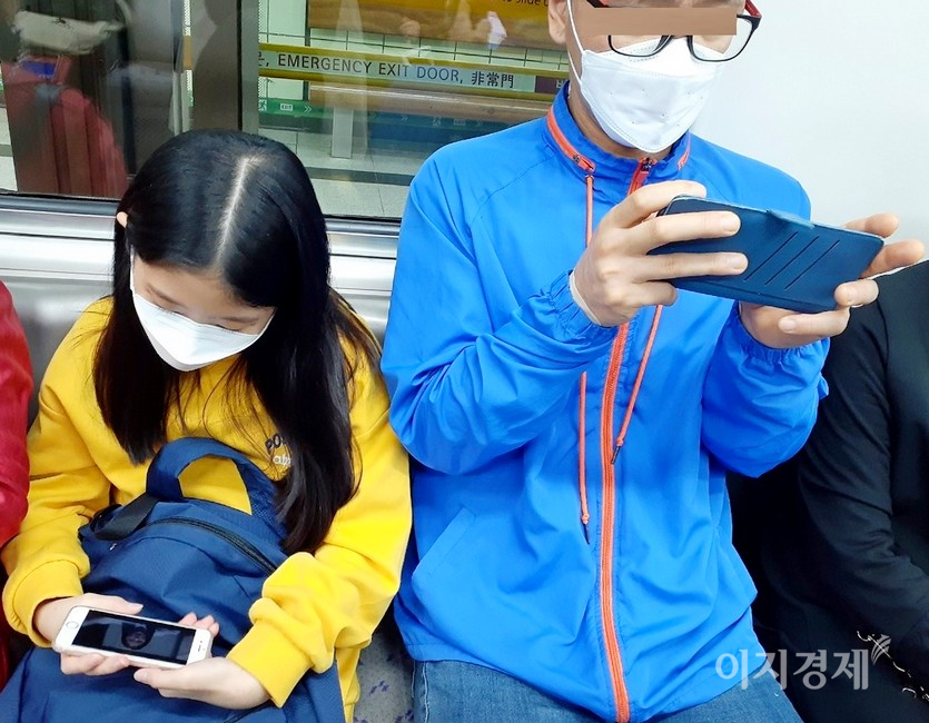 서울지하철 객차에서 부녀가 나란히 앉아 스마트폰 삼매경에 빠졌다. 사진=정수남 기자
