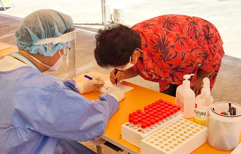 복권기금의 일자리 지원사업에 참여하고 있는 고주하(왼쪽) 씨가 제주 동부보건소 코로나 선별 진료소에서 방호복을 입고 문진 등 행정업무를 지원하고 있다. 사진=복권기금