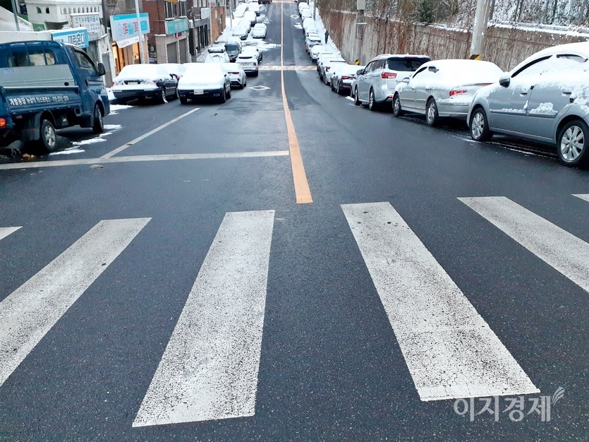 반면, 이면도로는 염화칼슘을 뿌려 차량이 경사 45℃ 의 도로도 평소처럼 달리고 있다. 이면도로 인도에도 염화칼슘이 뿌려졌다. 사진=김진이 기자
