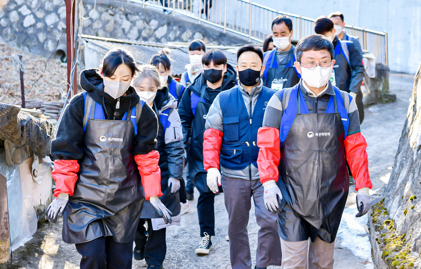 안도걸 차관과 김소연 단장, 봉사단원들이 지게로 연탄을 나르고 있다. 안 차관과 김 단장이 연탄을 나르며 구호를 외치고 있다. 사진=동행복권