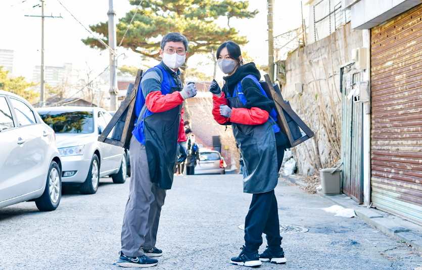 안도걸 차관과 김소연 단장, 봉사단원들이 지게로 연탄을 나르고 있다. 안 차관과 김 단장이 연탄을 나르며 구호를 외치고 있다. 사진=동행복권