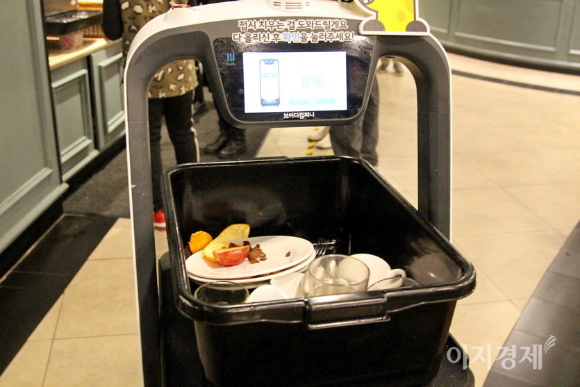 그룻을 모두 실은 푸드봇은 퇴식구로 가고, 그곳에서 직원이 대형 식기세척기에 그릇을 넣는다. 사진=김진이 기자