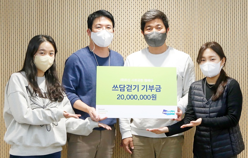 두산 임직원이 쓰담걷기로 조성한 2000만원의 기부금을 사회복지시설에 전달하고 있다. 사진=두산
