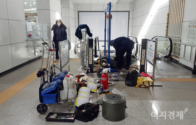 승객들이 에스컬레이터 수리하는 모습을 보면서 계단을 오르고 있다. 사진=김진이 기자
