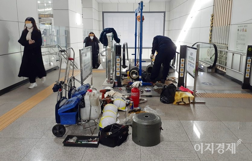 승객들이 에스컬레이터 수리하는 모습을 보면서 계단을 오르고 있다. 사진=김진이 기자