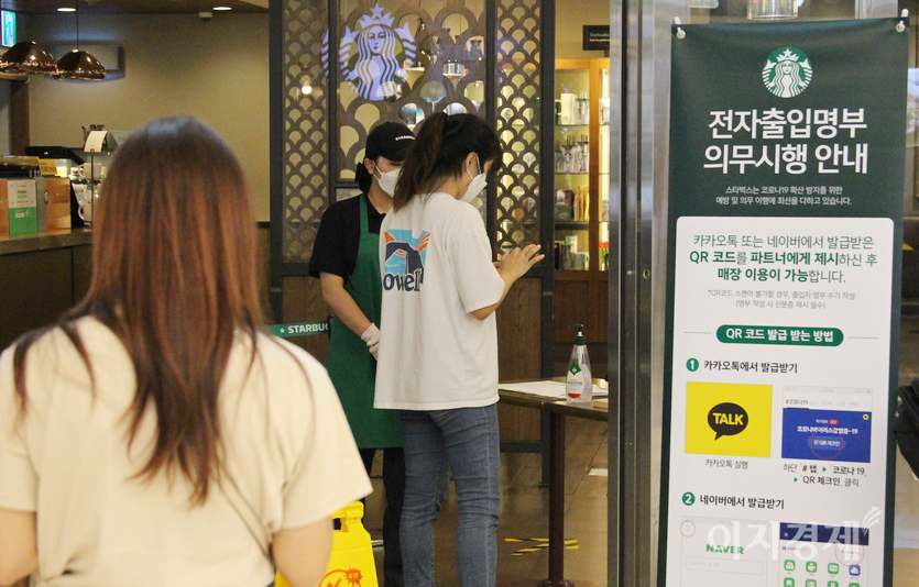 반면, 정부가 2020년 중반 전자출입명부 의무시행을 도입하자, 스타벅스 코엑스점 직원이 출입문에서 고객의 큐알 코드 적용 여부를 직접 확인하고 있다. (위부터)2020년 11월 8일과 12월 16일 모습. 사진=정수남 기자