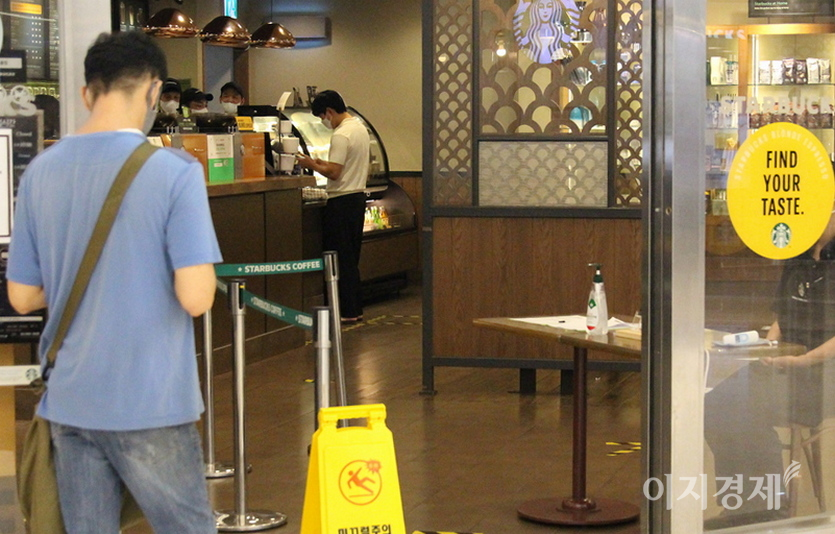 반면, 정부가 2020년 중반 전자출입명부 의무시행을 도입하자, 스타벅스 코엑스점 직원이 출입문에서 고객의 큐알 코드 적용 여부를 직접 확인하고 있다. (위부터)2020년 11월 8일과 12월 16일 모습. 사진=정수남 기자