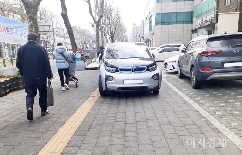 BMW의 i3이 인도 중앙제 당당히 주차해 있다. 유모차를 끌로 한 아이 엄마가 i3를 피해 걸어가고 있다. 사진=이승렬 기자