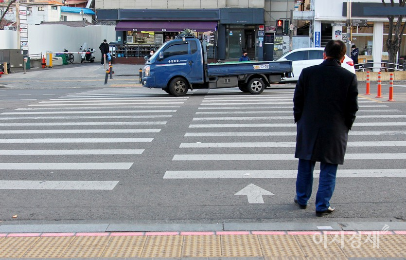 입식 신호등과 바닥 신호등에 빨간불이 들어왔다. 보행자가 대기하고 있는 가운데, 1톤 용달차가 달리다, 사진=김진이 기자