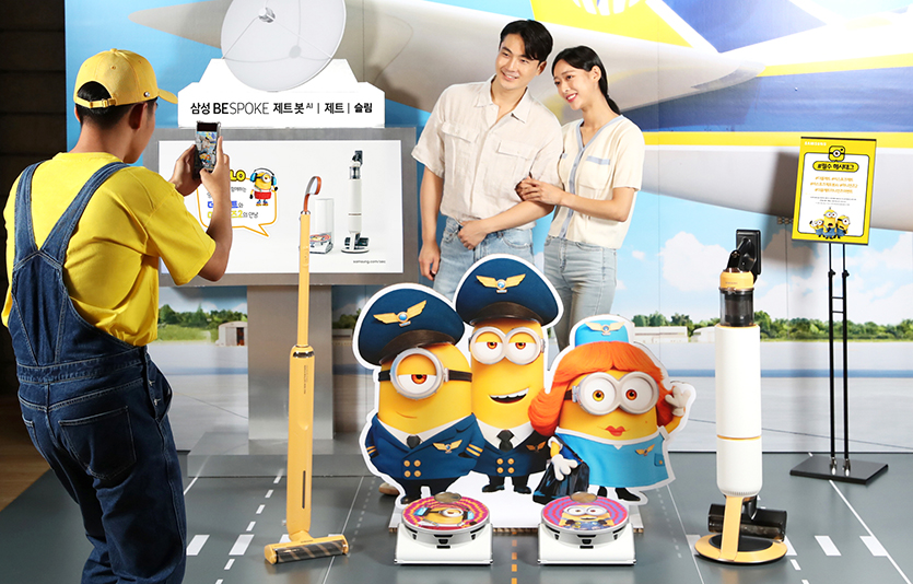 삼성전자가 ‘미니언즈2’와 협업한 비스포크 제트 봇 AI 특별 패키지 출시를 기념해 비스포크 제트·제트 봇 AI와 미니언즈2가 함께 꾸며진 포토존을 운영한다. 삼성전자 모델이 서울 강남구에 위치한 메가박스 코엑스점에서 운영 중인 포토존에서 특별 패키지를 소개하고 있는 모습. 사진=삼성전자