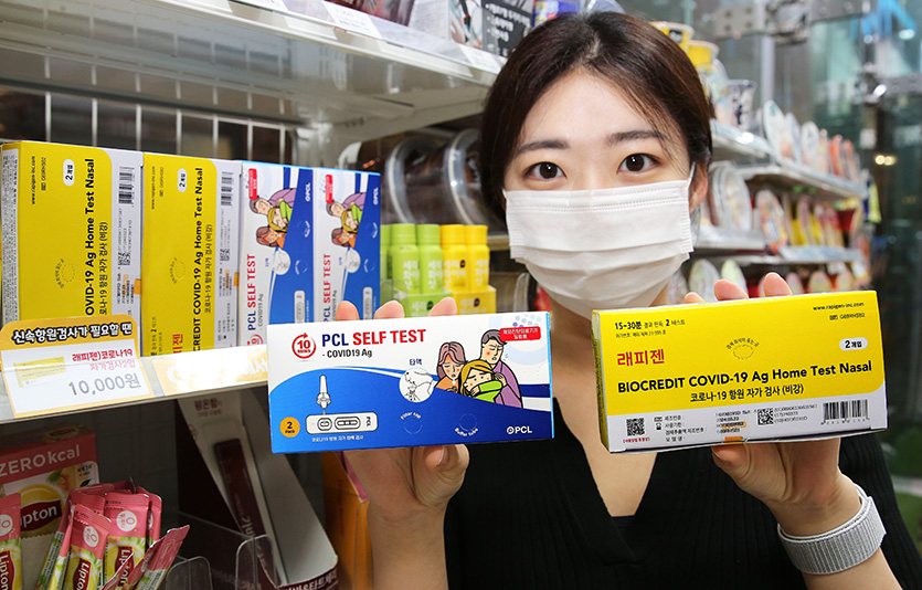 GS25에서 모델이 PCL타액검사키트(왼쪽)와 래피젠자가검사키트(오른쪽)를 들고 포즈를 취하고 있다. 사진=GS25