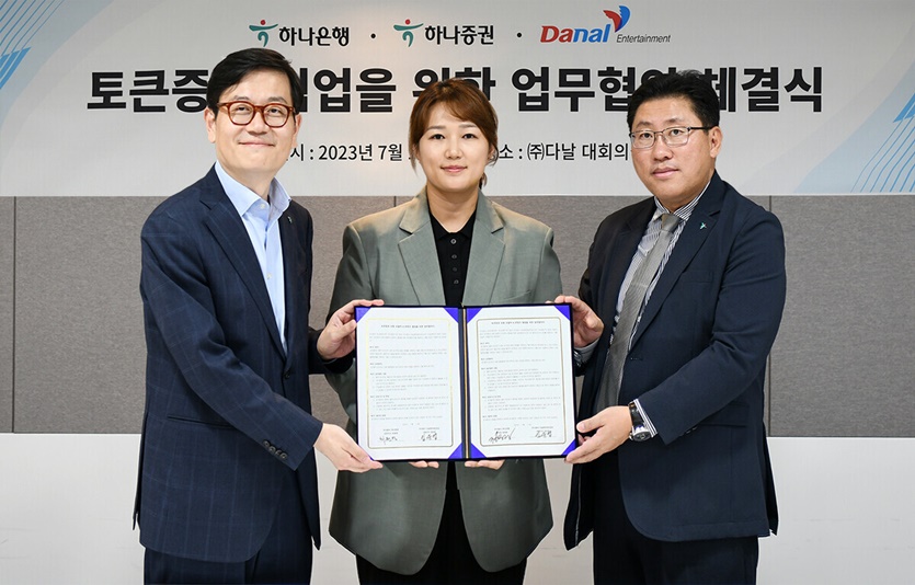 (왼쪽부터)정재욱 하나은행 디지털전략본부장, 임유엽 다날엔터테인먼트 대표, 최원영 하나증권 디지털본부 상무가 협약서를 들고 기념촬영을 하고 있다. 사진=하나은행