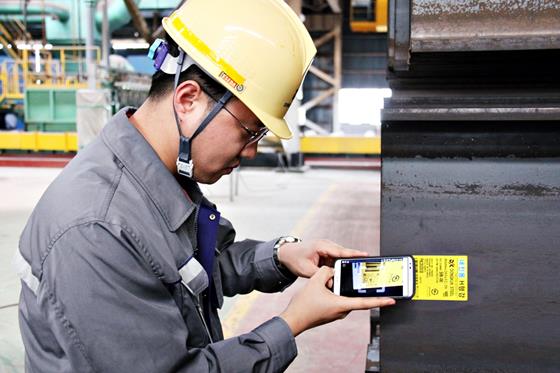 H형강에 부착된 업그레이드 스마트 라벨의 QR코드를 스마트폰으로 인식하는 동국제강 직원. 사진=동국제강